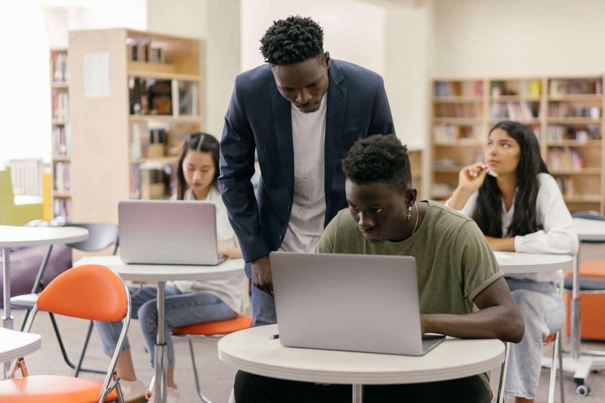 Instructor helping a student on a laptop in a classroom